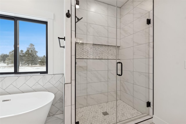 bathroom featuring a stall shower, tile walls, and a soaking tub