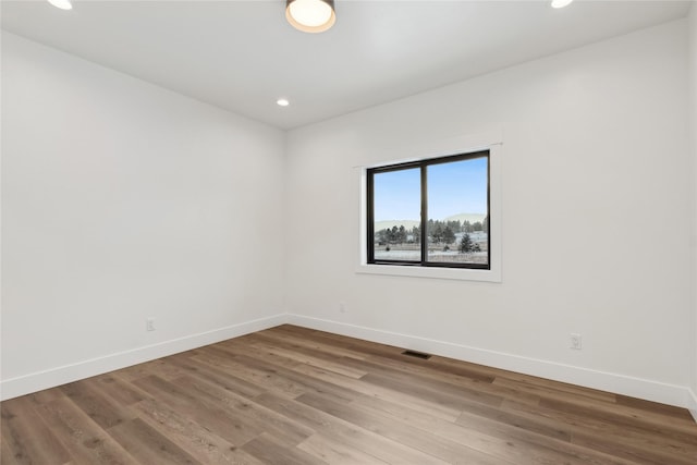 spare room with recessed lighting, visible vents, baseboards, and wood finished floors