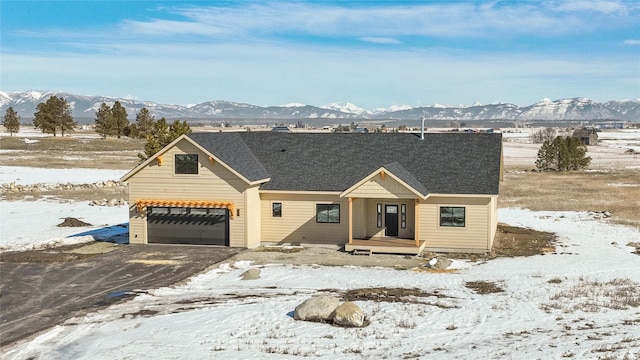 view of front of house featuring a garage, driveway, a shingled roof, and a mountain view