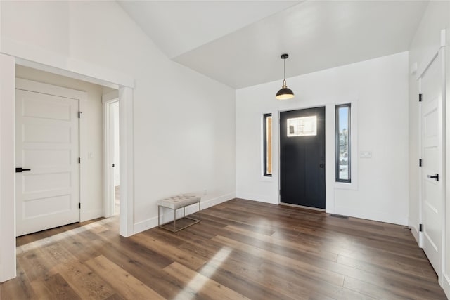 foyer with visible vents, baseboards, vaulted ceiling, and wood finished floors