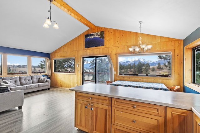 kitchen featuring a wealth of natural light, lofted ceiling with beams, pendant lighting, and an inviting chandelier