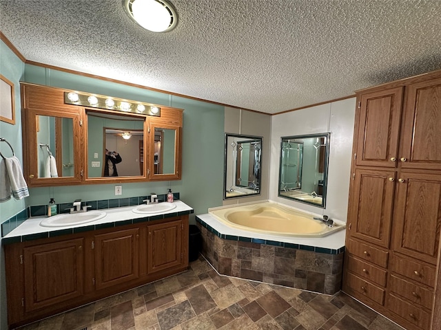 bathroom with ornamental molding, vanity, a textured ceiling, and a tub