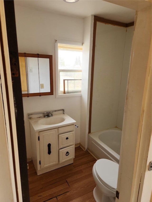 full bathroom featuring a bathing tub, toilet, wood finished floors, and vanity