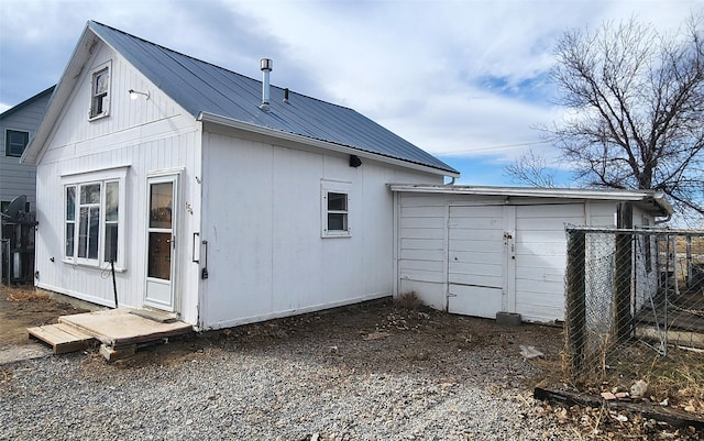 rear view of property with metal roof, an outdoor structure, and fence