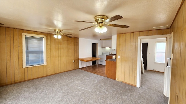 kitchen with visible vents, baseboards, washer / dryer, wood walls, and dark colored carpet