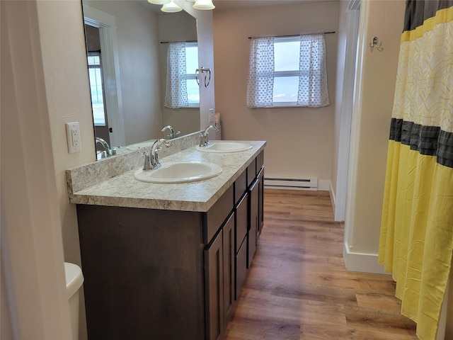 bathroom featuring hardwood / wood-style flooring, vanity, toilet, and a baseboard heating unit