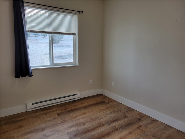 empty room featuring hardwood / wood-style floors, plenty of natural light, and baseboard heating