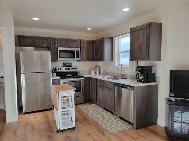 kitchen featuring appliances with stainless steel finishes, light hardwood / wood-style floors, dark brown cabinets, and sink