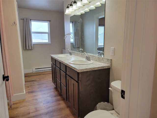 bathroom featuring toilet, vanity, wood-type flooring, and a baseboard heating unit