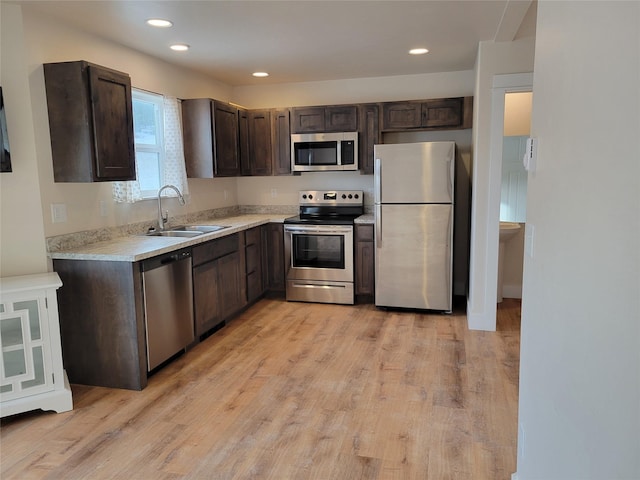 kitchen featuring dark brown cabinets, sink, light wood-type flooring, and stainless steel appliances