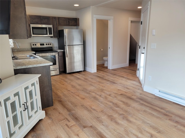 kitchen with sink, baseboard heating, appliances with stainless steel finishes, dark brown cabinets, and light hardwood / wood-style floors