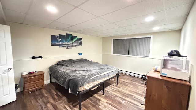 bedroom featuring hardwood / wood-style floors, a drop ceiling, and a baseboard heating unit