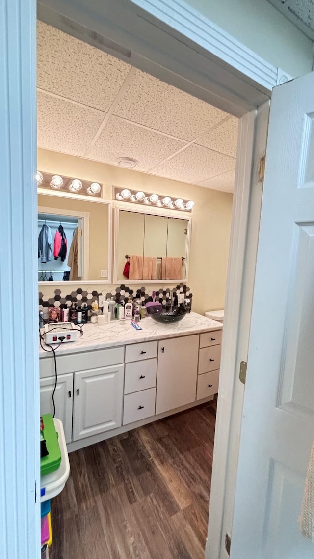 bathroom with a paneled ceiling, hardwood / wood-style floors, and vanity