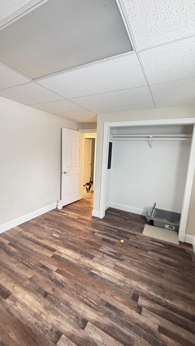 basement featuring a paneled ceiling and dark wood-type flooring