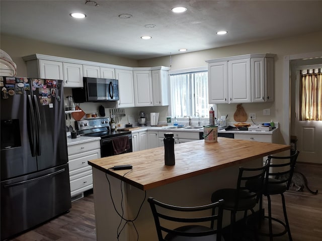 kitchen with white cabinets, a breakfast bar, stainless steel appliances, and butcher block counters