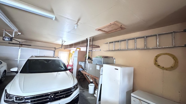 garage with a garage door opener and white refrigerator