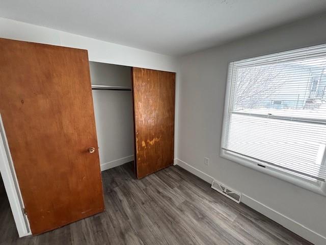 unfurnished bedroom featuring dark hardwood / wood-style flooring and a closet