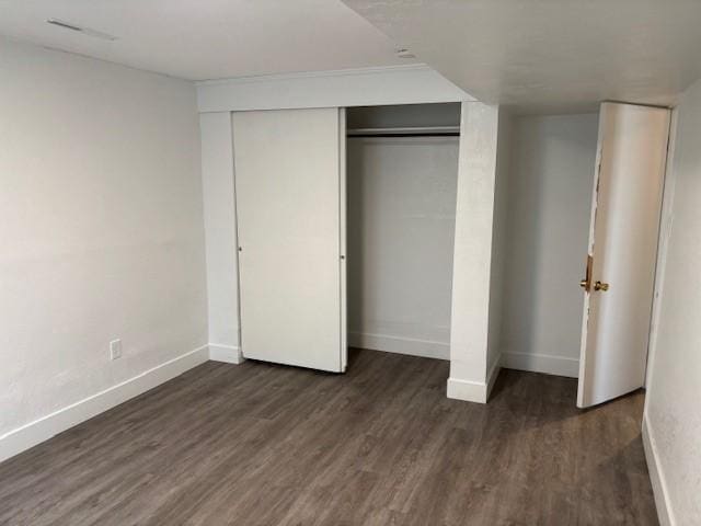 unfurnished bedroom with dark hardwood / wood-style flooring and a closet