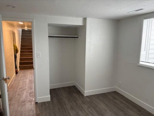 unfurnished bedroom with dark hardwood / wood-style flooring and a closet