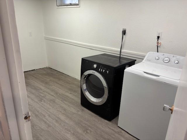 laundry area with light hardwood / wood-style flooring and washer and dryer