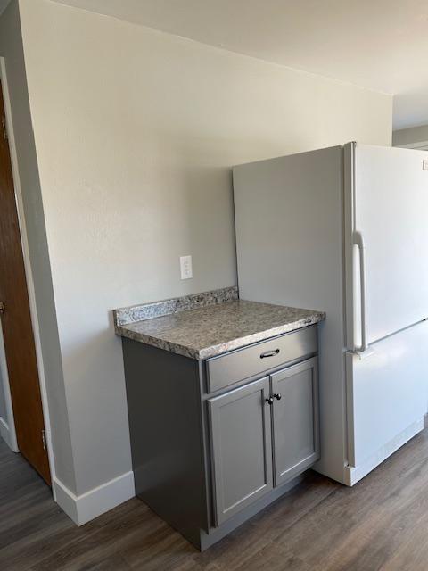 kitchen featuring gray cabinets, white refrigerator, and dark hardwood / wood-style flooring