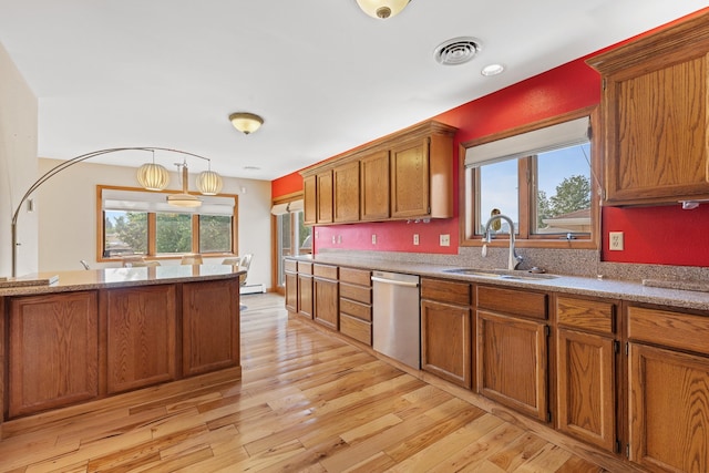 kitchen featuring dishwasher, sink, light stone counters, pendant lighting, and light hardwood / wood-style floors