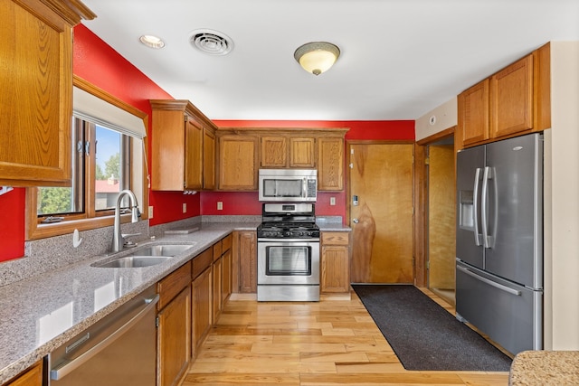 kitchen featuring light stone counters, sink, light wood-type flooring, and stainless steel appliances