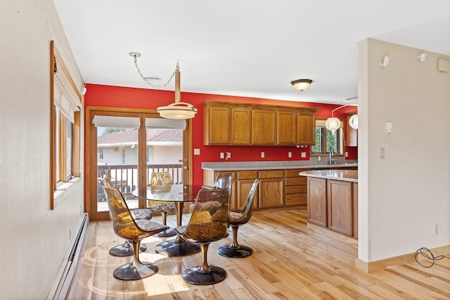 kitchen featuring decorative light fixtures, light hardwood / wood-style floors, sink, and baseboard heating