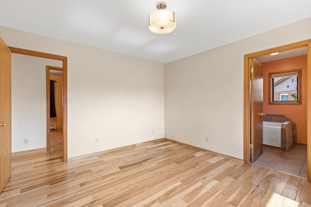 empty room featuring baseboard heating and light wood-type flooring