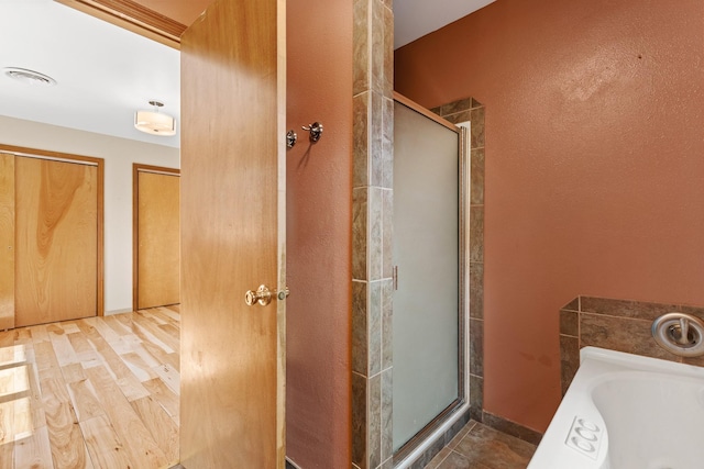 bathroom with separate shower and tub and wood-type flooring