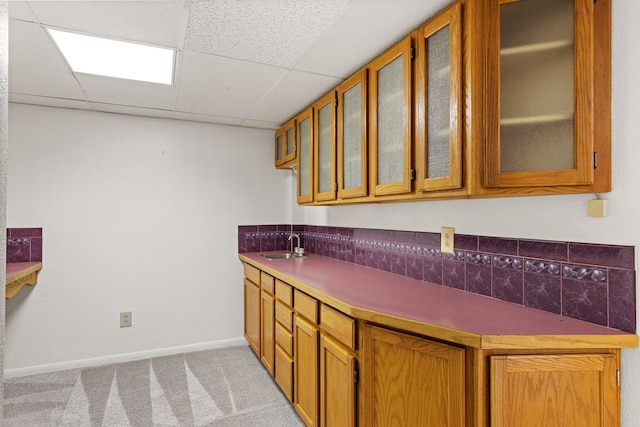 kitchen featuring a drop ceiling, light colored carpet, and sink