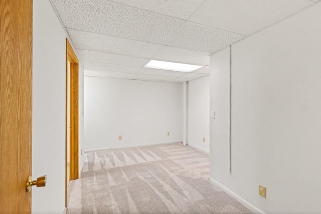 basement with a paneled ceiling and light carpet