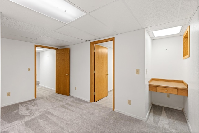 basement featuring light colored carpet and a drop ceiling