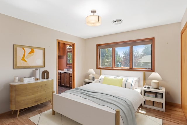 bedroom featuring wood-type flooring and ensuite bath