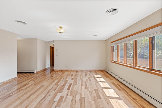 empty room with light hardwood / wood-style floors and a baseboard heating unit