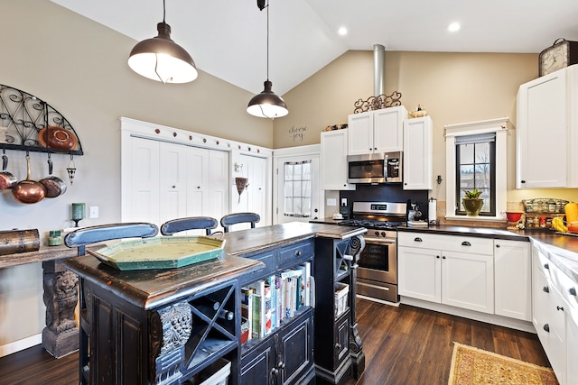 kitchen featuring white cabinets, decorative light fixtures, a kitchen island, dark hardwood / wood-style flooring, and stainless steel appliances