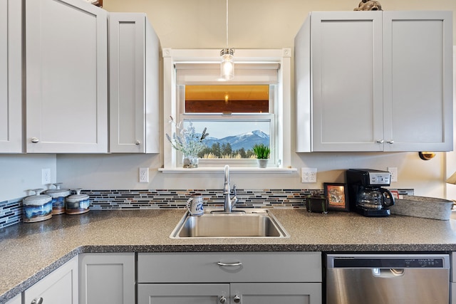 kitchen featuring stainless steel dishwasher, decorative light fixtures, white cabinetry, and sink