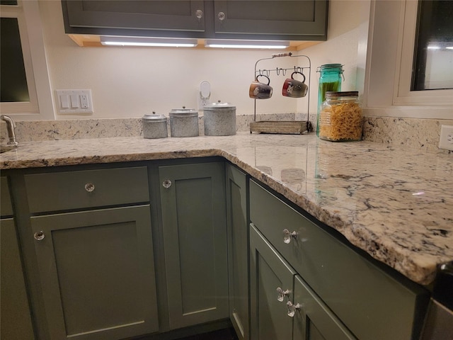 kitchen with green cabinets and light stone countertops