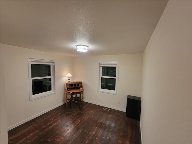 spare room featuring dark hardwood / wood-style floors and a textured ceiling