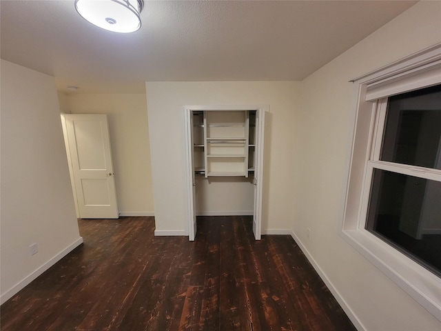 unfurnished bedroom featuring dark wood-type flooring and a closet