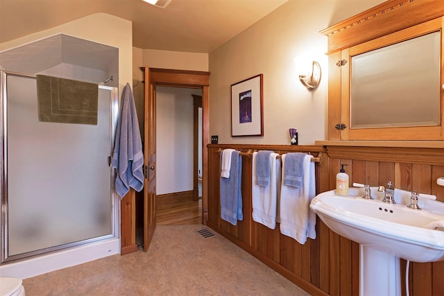 bathroom featuring a shower with shower door and wood walls