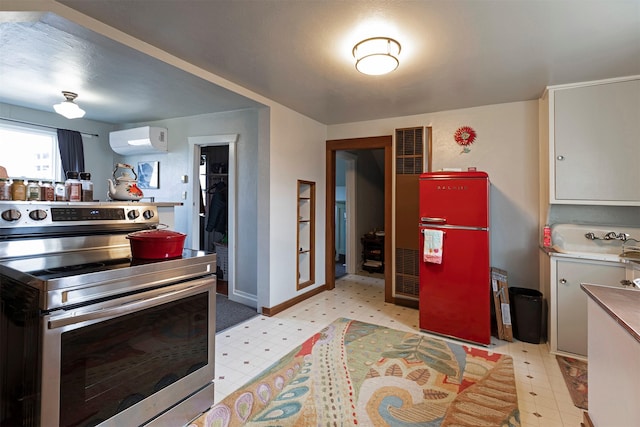 kitchen featuring stainless steel electric stove, refrigerator, white cabinets, and a wall mounted AC