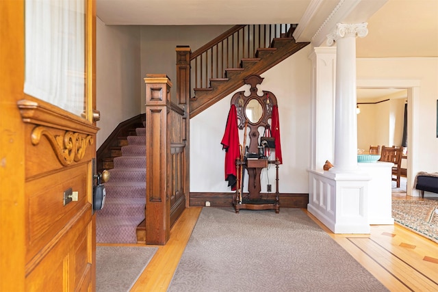 entrance foyer with decorative columns and light hardwood / wood-style floors