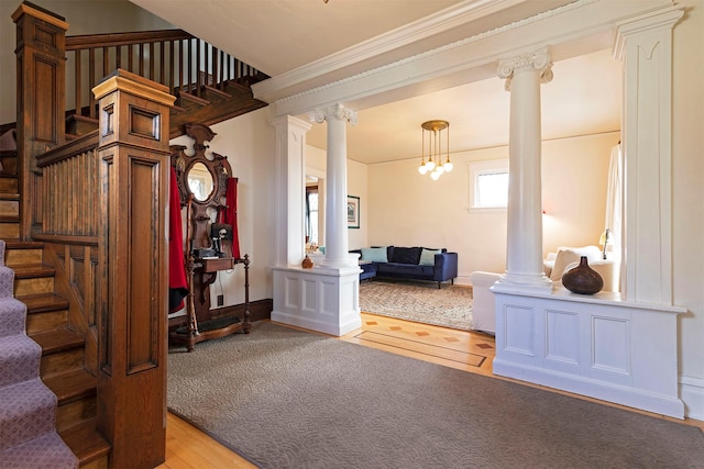 interior space with ornate columns, ornamental molding, a notable chandelier, and light wood-type flooring