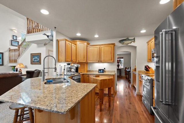 kitchen featuring kitchen peninsula, a breakfast bar, stainless steel appliances, sink, and dark hardwood / wood-style floors