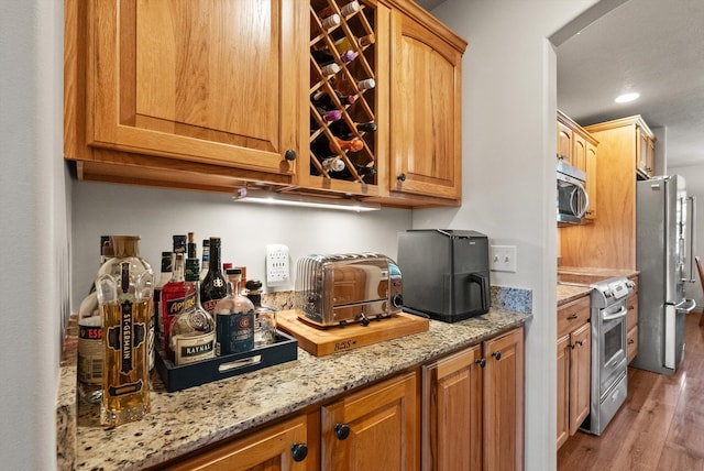 kitchen featuring light hardwood / wood-style floors, light stone counters, and stainless steel appliances