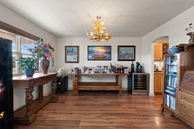 interior space featuring wine cooler, dark wood-type flooring, and a notable chandelier