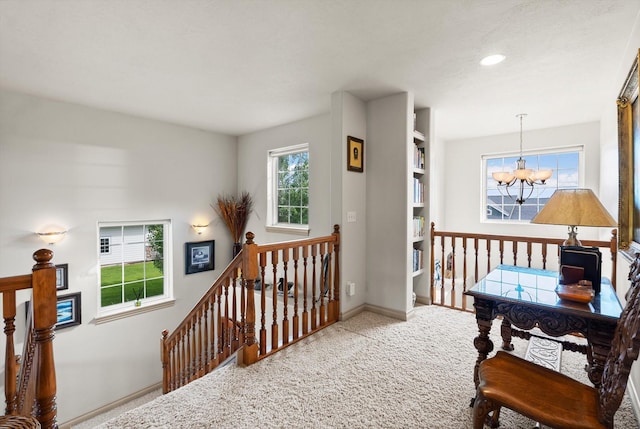 hallway with built in features, light colored carpet, and a notable chandelier