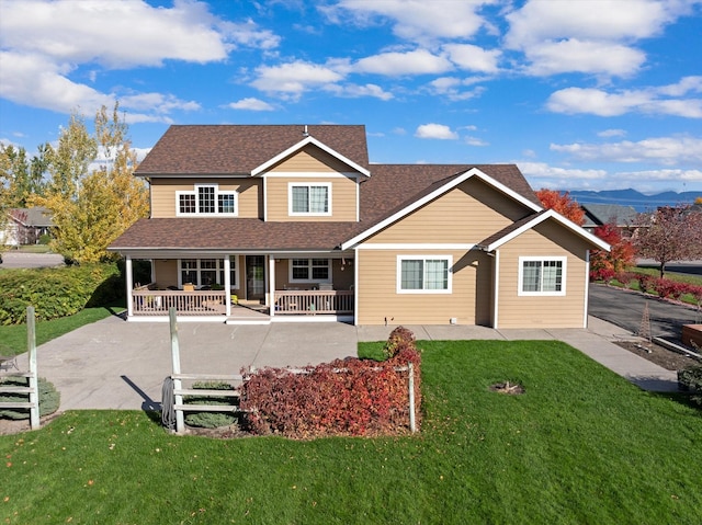 view of front of home with covered porch, a mountain view, and a front lawn