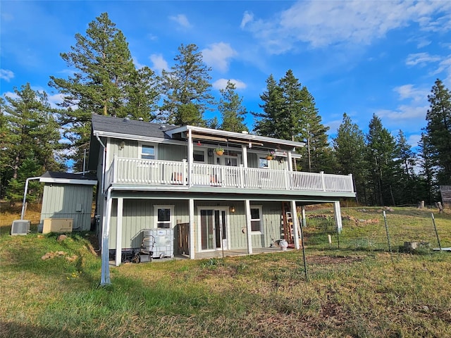 rear view of property featuring a yard, central AC unit, board and batten siding, and a wooden deck